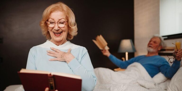Elderly Couple Reading Books Before Bedtime At Memory Care Facility