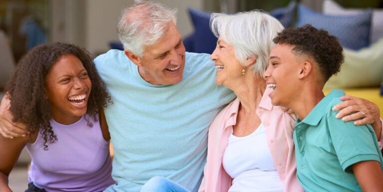 Elderly Couple Laughing and Hugging with Grandchildren at a Memory Care Facility