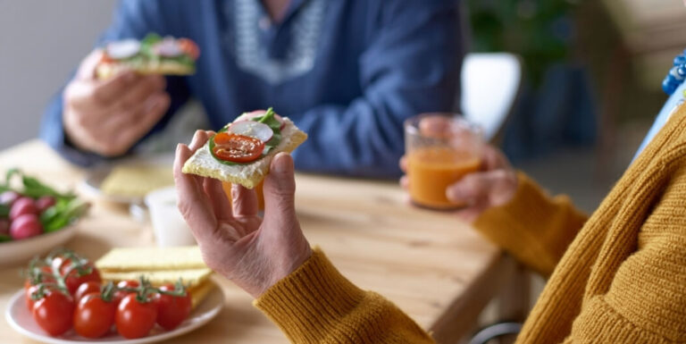 Seniors Eating Finger Foods Together at a Dining Table at a Memory Care Facility