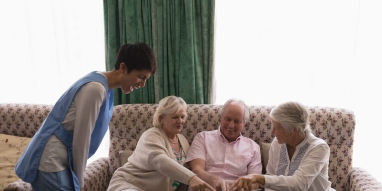 Female Nurse Showing a Tablet to Smiling Elderly Residents at Memory Care Facility